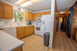 A modern kitchen with wooden cabinets, a white refrigerator, a microwave, and a dishwasher. - Ludwig's Lodge: 5 Bedroom, 3 bathroom Dollar Point home. (Tahoe City)