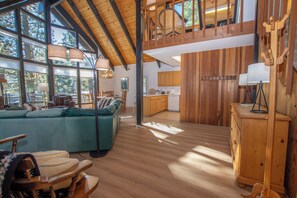A spacious living area with a large sofa, wooden flooring, and a kitchen in the background. - Ludwig's Lodge: 5 Bedroom, 3 bathroom Dollar Point home. (Tahoe City)