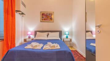 A hotel room with a bed, two bedside lamps, a painting, and a mirror.