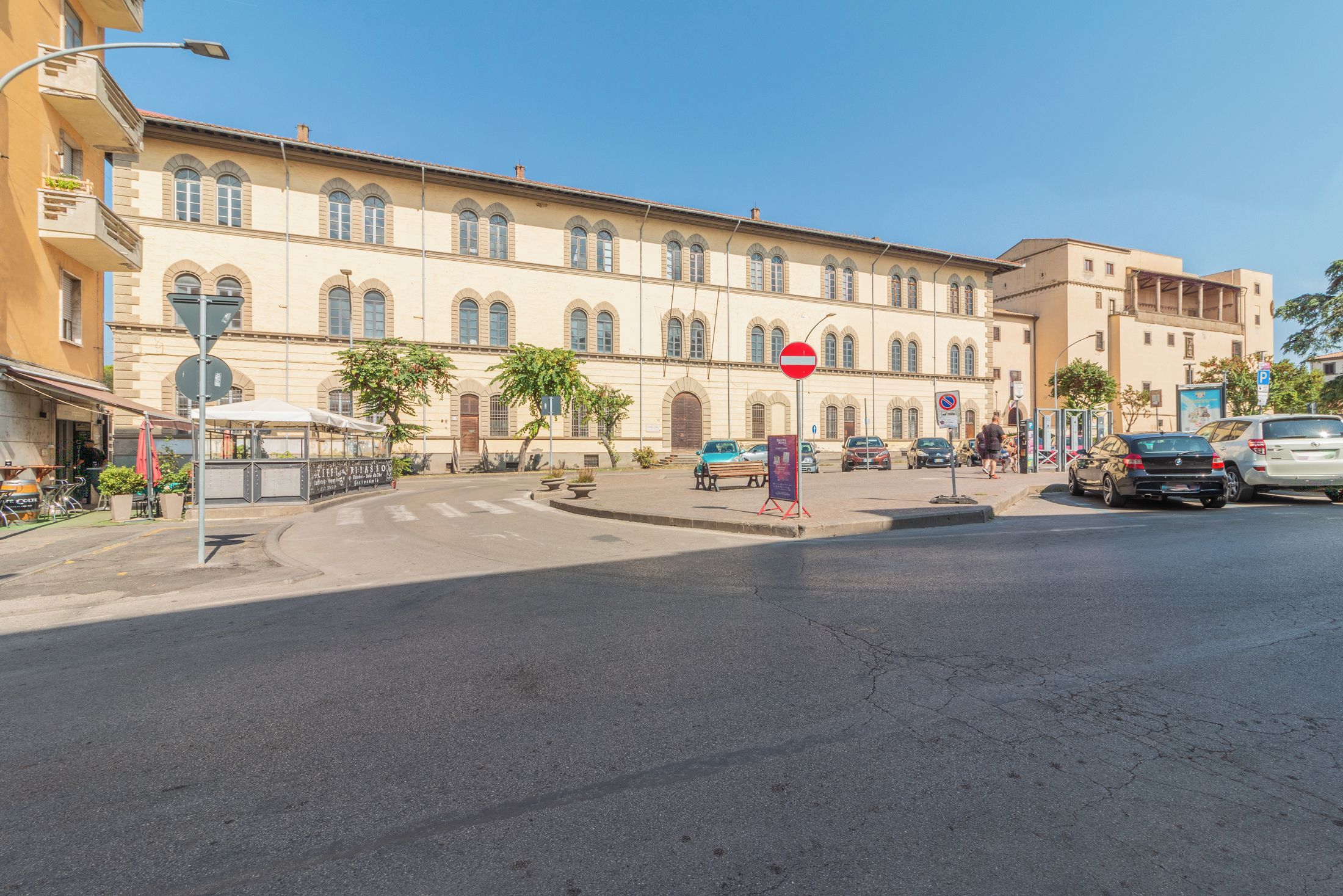 A street view with a building featuring arched windows and a clear sky.