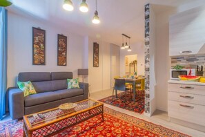 A modern living room with a sofa, coffee table, and a dining area with a table and chairs. - Pettinara Suites (Viterbo)