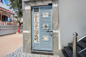 Puerta azul con diseños decorativos y una cerradura, que da paso a un edificio con entrada de azulejos y una escalera.