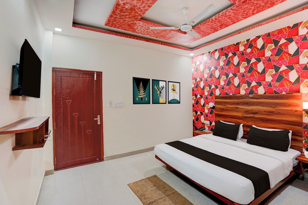 Habitación de hotel con cama, cabecero de madera, puerta roja y ventilador de techo.