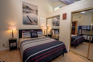Ein Hotelzimmer mit einem großen Bett, zwei Nachttischen, einem Spiegel und Kunstwerken an der Wand.