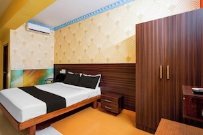 A hotel room with a bed, a wooden wardrobe, a bedside table, and an air conditioning unit. - Super Hotel O Mathikere Extension (Bangalore)