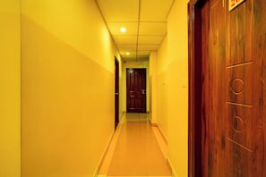 A corridor with a wooden door on the right and a closed door at the end.