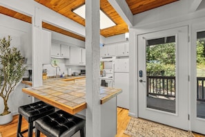 Eine moderne Küche mit weißen Schränken, einer Holz Arbeitsplatte und einem Blumentopf.