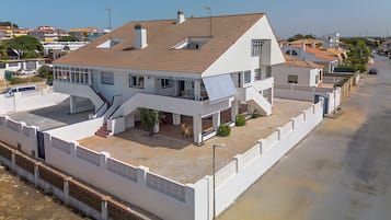 A two-story residential building with a flat roof, a balcony, and a covered patio area.
