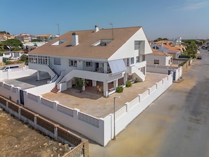 Un edifici residencial de dues plantes amb teulada plana, un balcó i una zona de pati coberta.