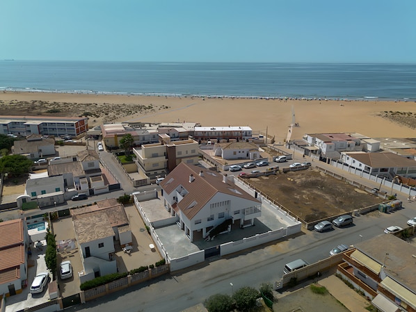 Zona residencial a la costa amb cases, una platja i cel blau.