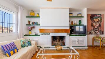 Een woonkamer met een open haard, een bank, een salontafel en een televisie.