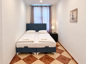 Ein Hotelzimmer mit Bett, Nachttisch, Lampe und einem Bild an der Wand.