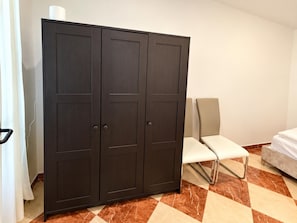Ein Zimmer mit Schrank, Stuhl und Bett.