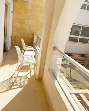 A balcony with a white metal railing, a small table, and two white plastic chairs. - Edelma Retreat 2BR Pool Views, Sahl Hasheesh (Red Sea Governorate)