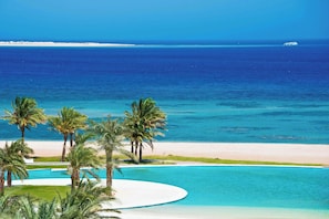 A beach resort with a swimming pool, palm trees, and a view of the ocean. - Edelma Retreat 2BR Pool Views, Sahl Hasheesh (Red Sea Governorate)