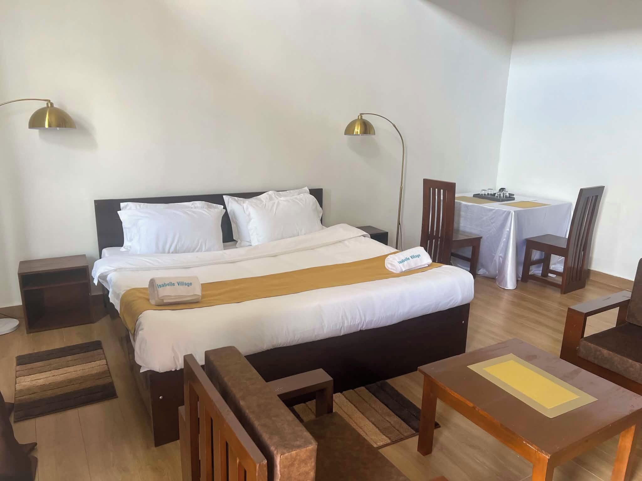 A hotel room with a bed, bedside lamps, a desk, and a chair.