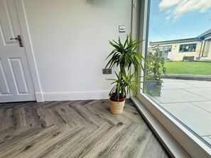 A room with a wooden floor, a potted plant, and a view of a house through a window. - Amazing guest house for a romantic get away (Edinburgh)