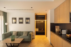 A modern living room with a sofa, a coffee table, and a kitchen area with wooden cabinets and a countertop. - Macsuites Central Market (Valencia)