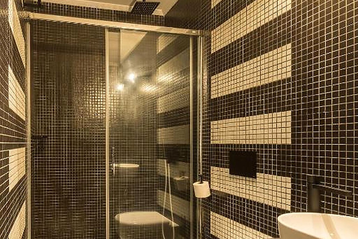 Un baño con ducha acristalada, inodoro y lavamanos.
