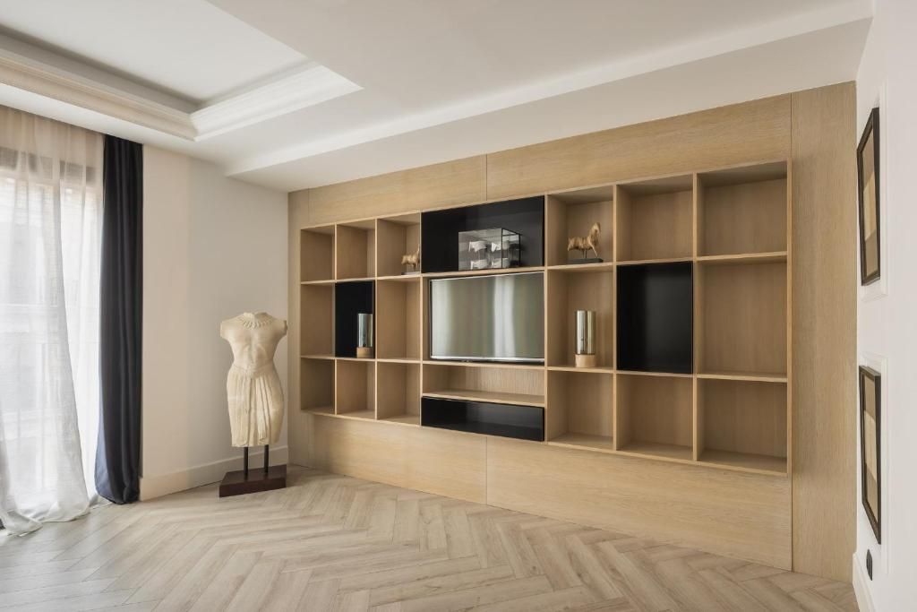 Una habitación con un mueble grande de madera para entretenimiento, un maniquí y un piso con diseño de espiga.