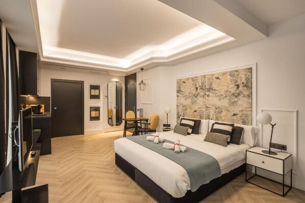 Habitación de hotel moderna con una cama grande, un escritorio, una silla y un cuadro abstracto de gran tamaño en la pared.