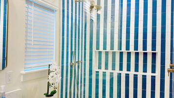 A bathroom with a white toilet, a sink, and a shower with blue-striped tiles.