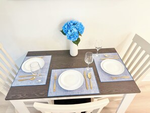 A dining table set with white plates, gold cutlery, and blue placemats. - Azure & Anchor Coastal Escape W Huge Fenced Yard & Fire Pit + Small-Pet-Friendly (St. Augustine)