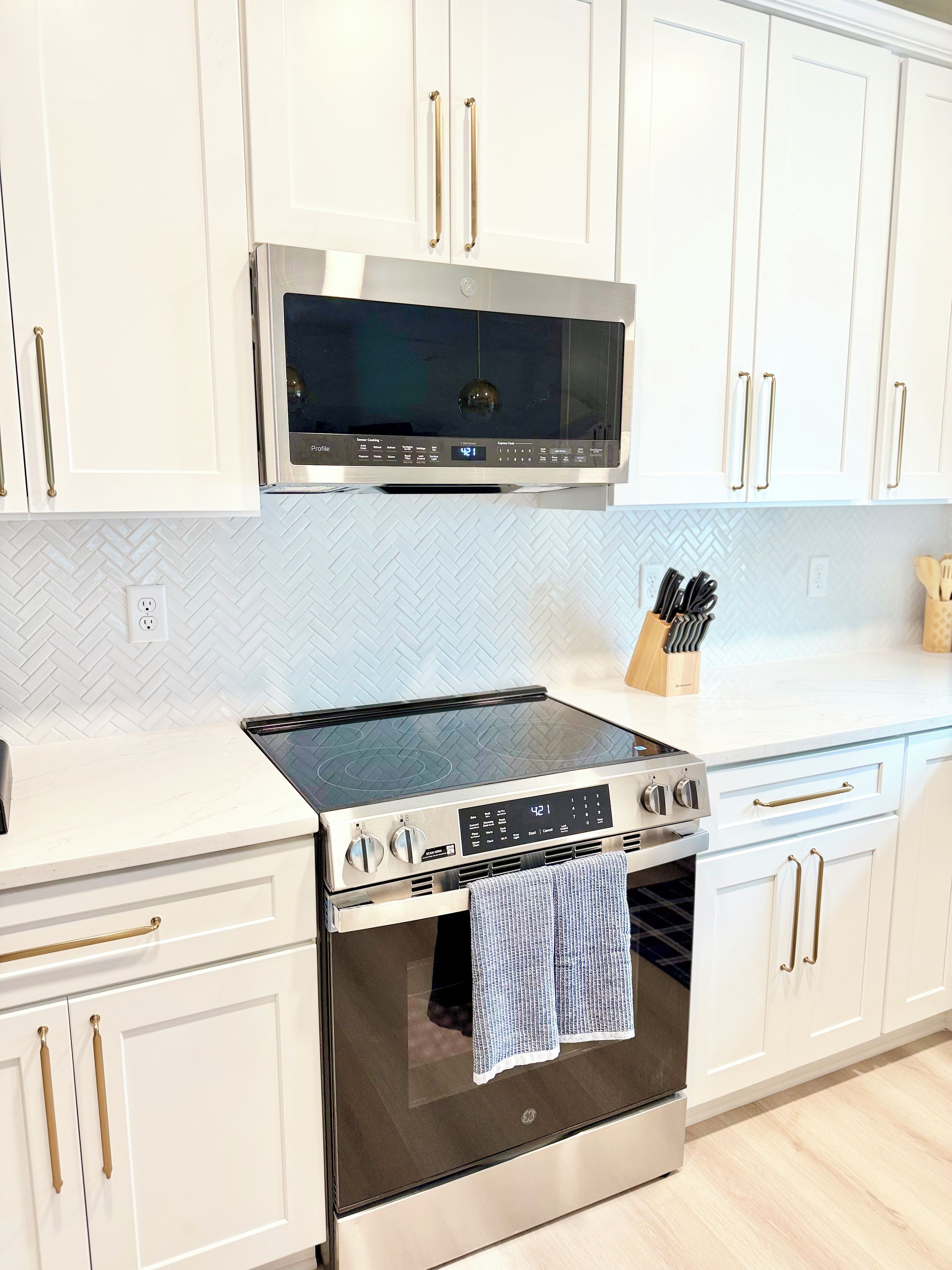 A kitchen with white cabinetry, a stainless steel range, and a built-in oven.