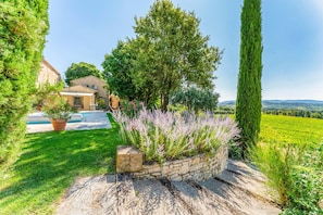 A stone house with a swimming pool, surrounded by lush greenery and a view of the countryside. - Villa Les Vignes - Four Bedroom Villa, Sleeps 10 (Joucas)