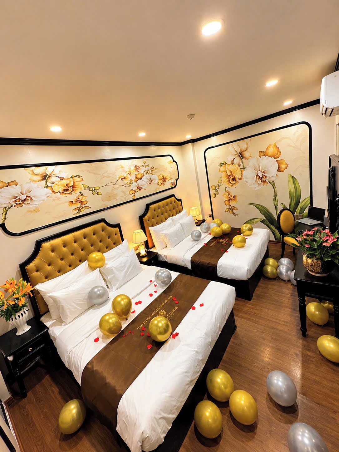 A hotel room with two beds, a large floral mural, and decorative balloons.