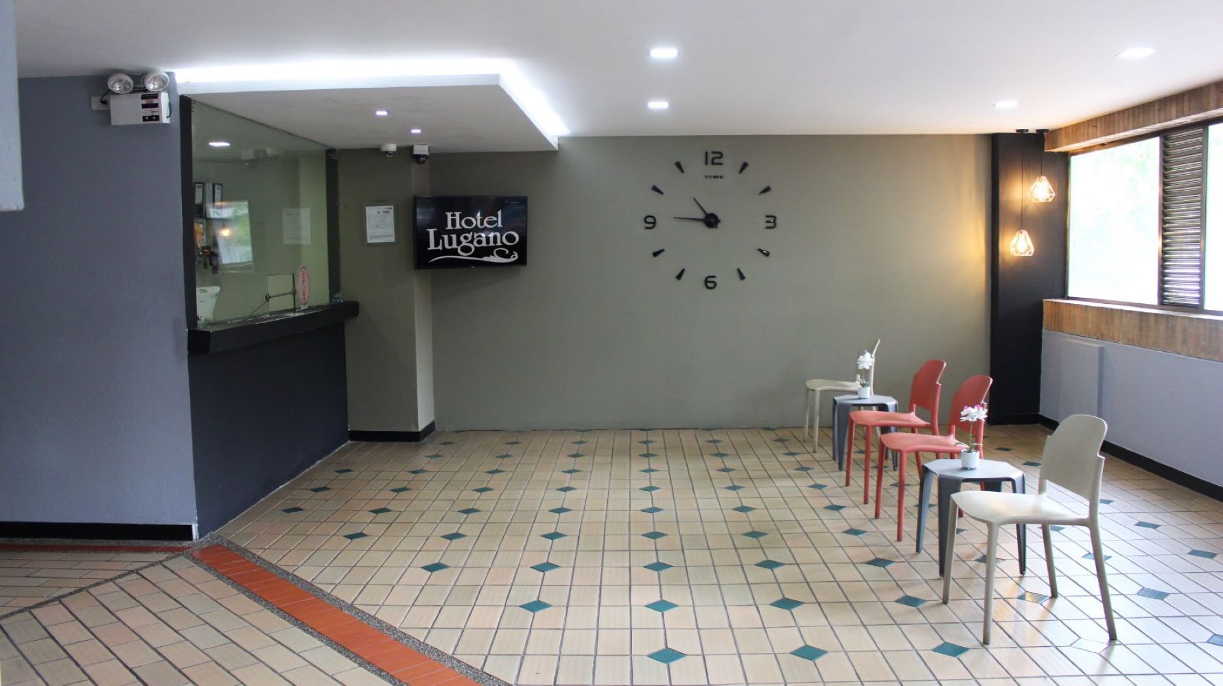 A hotel lobby with a clock, a reception desk, and several chairs.
