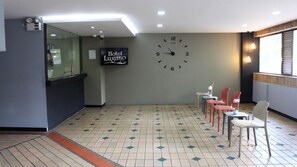 Un vestíbulo de hotel con un reloj, una recepción y varias sillas.