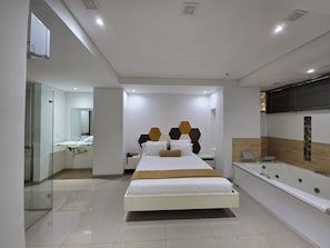A modern hotel room with a large bed, a separate bathroom, and a glass-enclosed shower area. - Hotel Lugano (Medellín)
