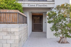 En bygningseingang med et skilt der siger 'Casa Flambo' og tallet '1053' på væggen.