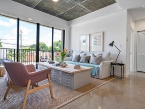A modern living room with a sofa, a coffee table, and a chair. There is a window with a view of the outdoors. - 201-Tropical Refuge Near Wynwood+Rubell Museum (Miami)