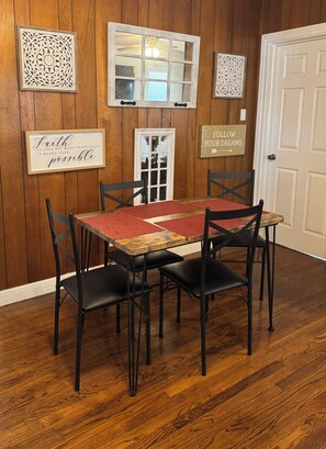 A dining area with a wooden table, black chairs, and decorative wall art. - The Cedar Cottage - Cozy 3BR/1BR Home Near Texas Tech (Lubbock)