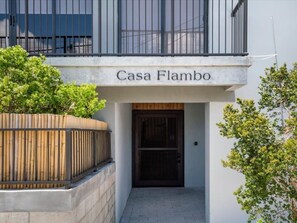 De ingang van een gebouw, aangeduid met 'Casa Flambo', met een houten hek en een donkere deur.