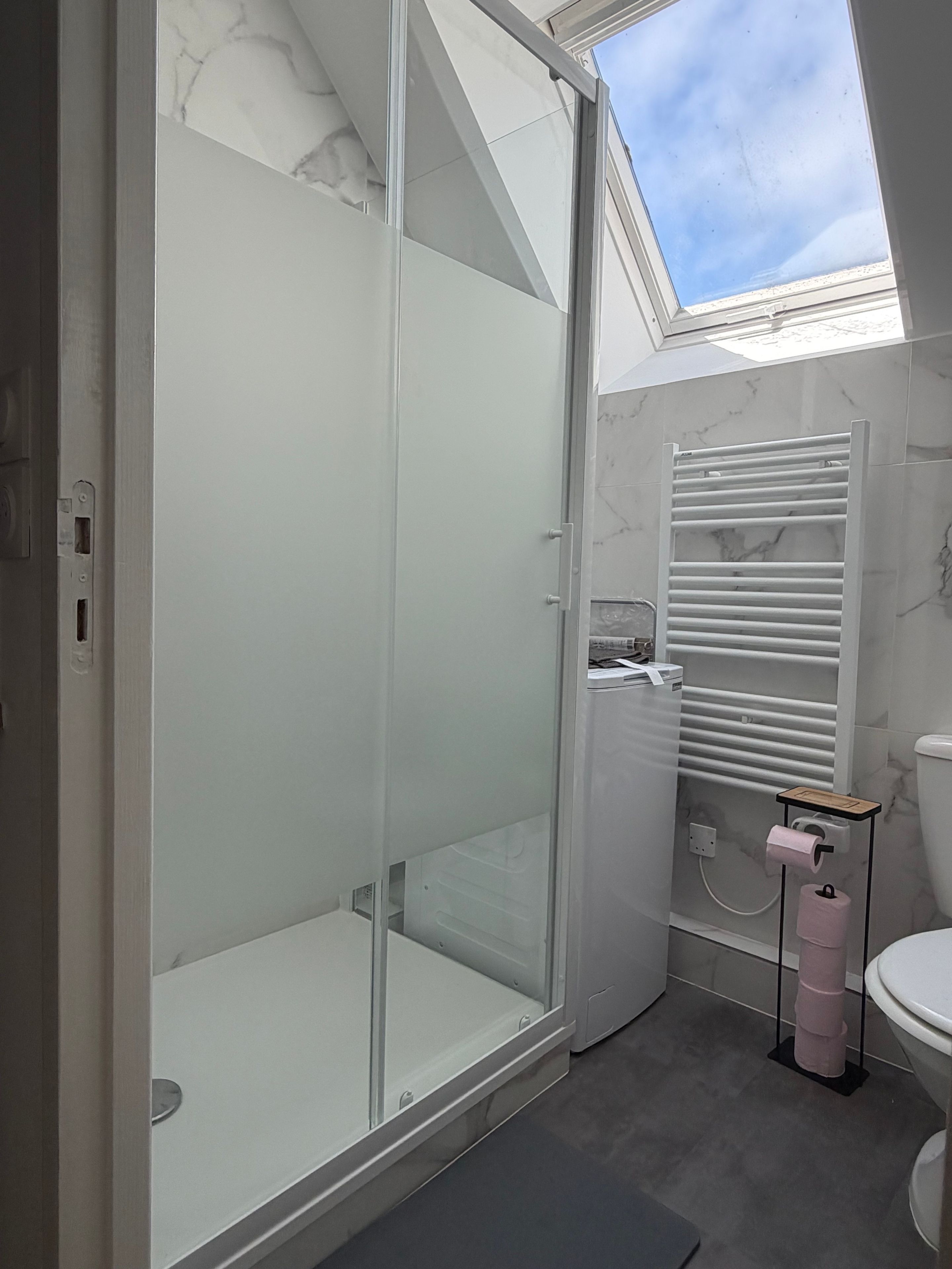 Een moderne badkamer met een douchecabine van glas, een toilet en een handdoekhouder.