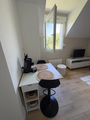 A compact living space with a dining table, chairs, a coffee machine, a TV, and a window with a view. - Studio 'Cocoon' with Wi-Fi (Erquy)