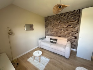 A living room with a sofa, a small round table, a floor lamp, a mirror, and a zebra-patterned wall. - Studio 'Cocoon' with Wi-Fi (Erquy)