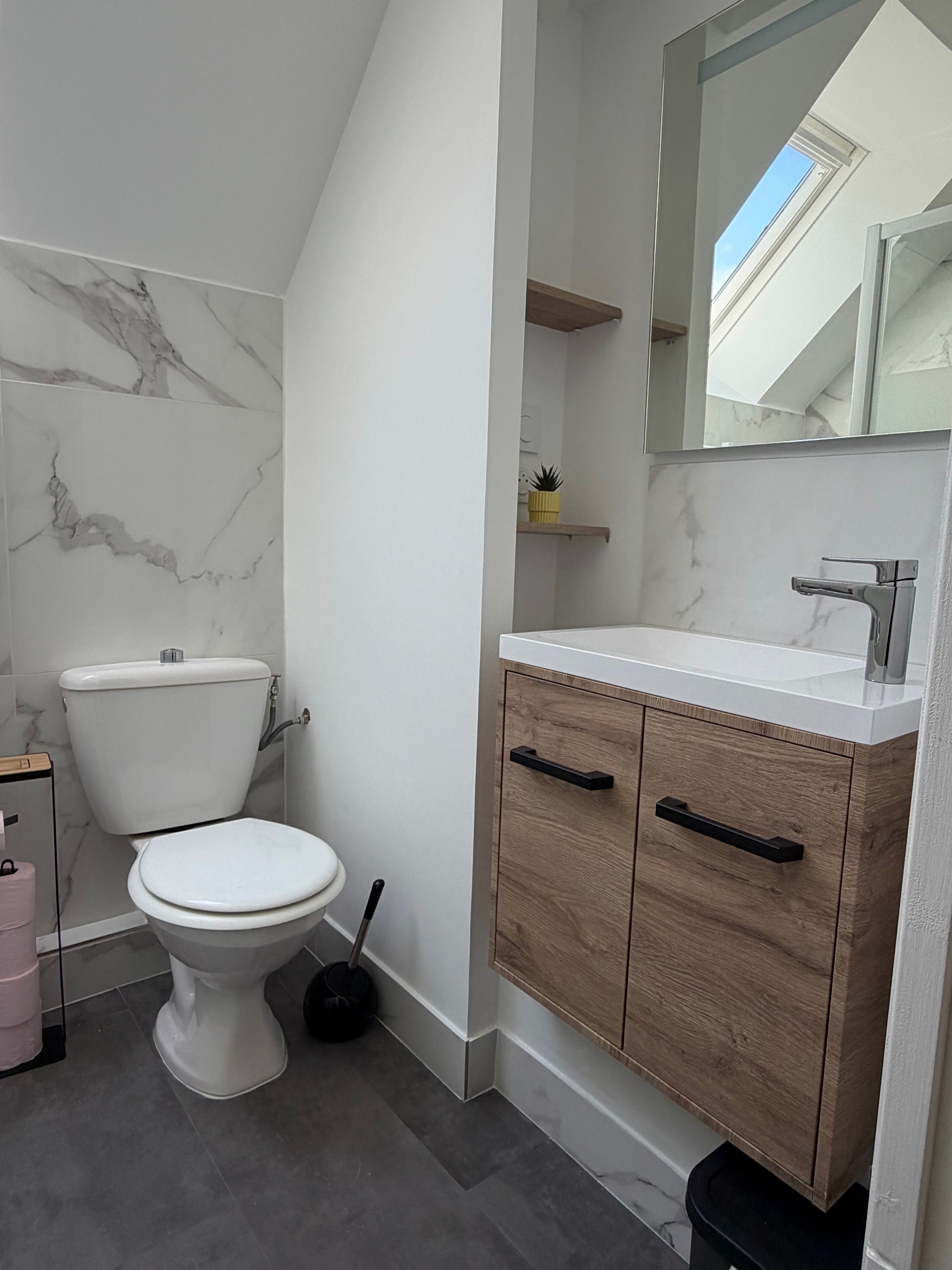 Ein modernes Badezimmer mit Toilette, Waschtisch und Spiegel.