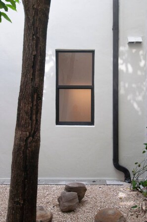 A building facade with a window, a tree, and a gravel area with rocks. - 301-Tropical Refuge Near Wynwood+Rubell Museum (Miami)