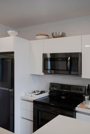 Eine moderne Küche mit einem Edelstahl-Kühlschrank, einer Mikrowelle und einem Backofen.