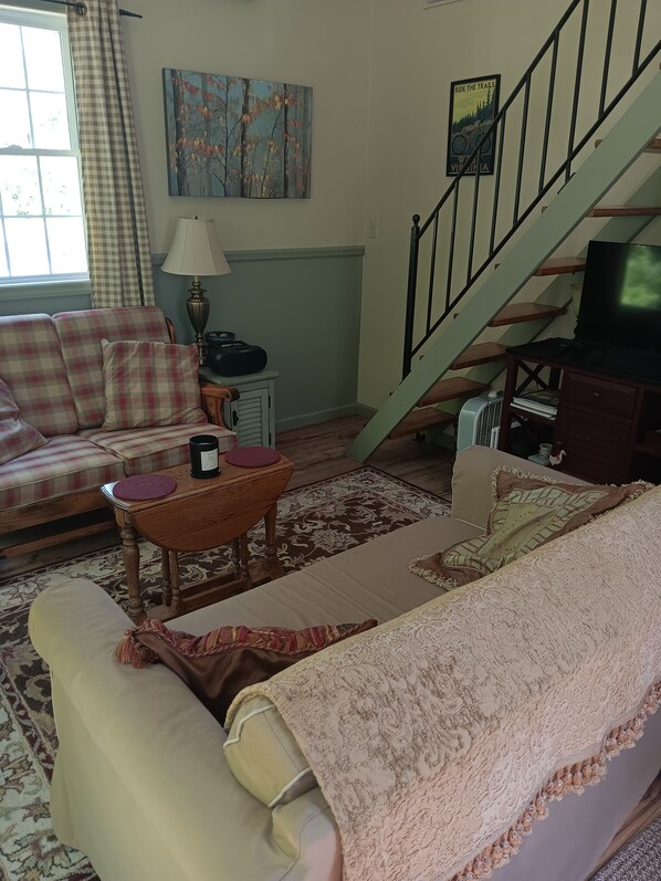 A living room with a sofa, a coffee table, a television, and a staircase.