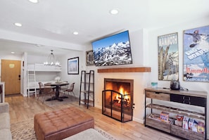 A modern living room with a fireplace, a dining area, and a kitchen. - Mammoth Nest Walk to Slopes Condo 655 (Mammoth Lakes)