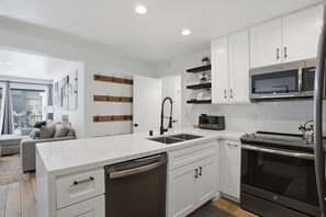 A modern kitchen with white cabinets, a stainless steel oven, and a built-in microwave. - Mammoth Nest Walk to Slopes Condo 655 (Mammoth Lakes)