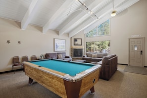 A pool table in a room with a high ceiling, a fireplace, and a door marked 'Max Occupancy 39'. - Mammoth Nest Walk to Slopes Condo 655 (Mammoth Lakes)