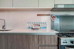 A kitchen with a marble countertop, a sink, a stove, and a sign indicating full safety. - HAVN - 5 Bed Villa at Talia, The Valley by EMAAR (Al Yufrah 1)