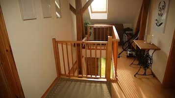 Ein schmaler Flur mit einer Holztreppe, die zu einem Erker führt.