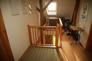 A narrow hallway with a wooden staircase leading to a loft area.